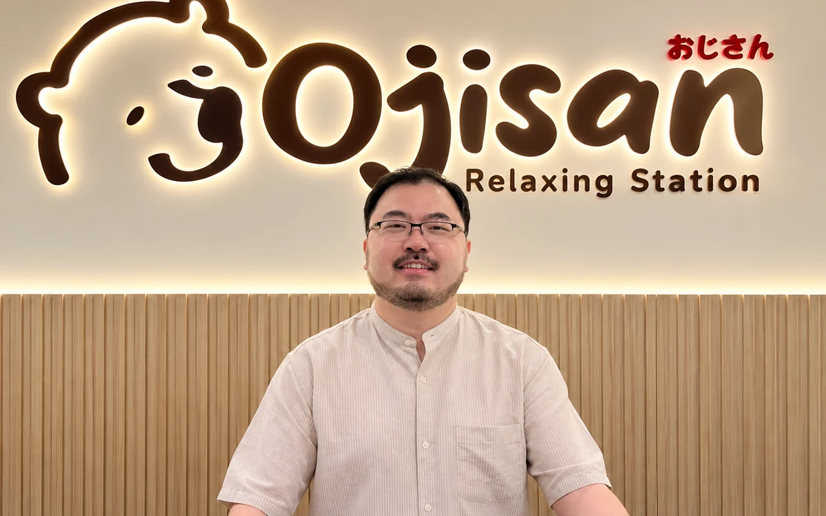A person standing in front of the Ojisan logo
