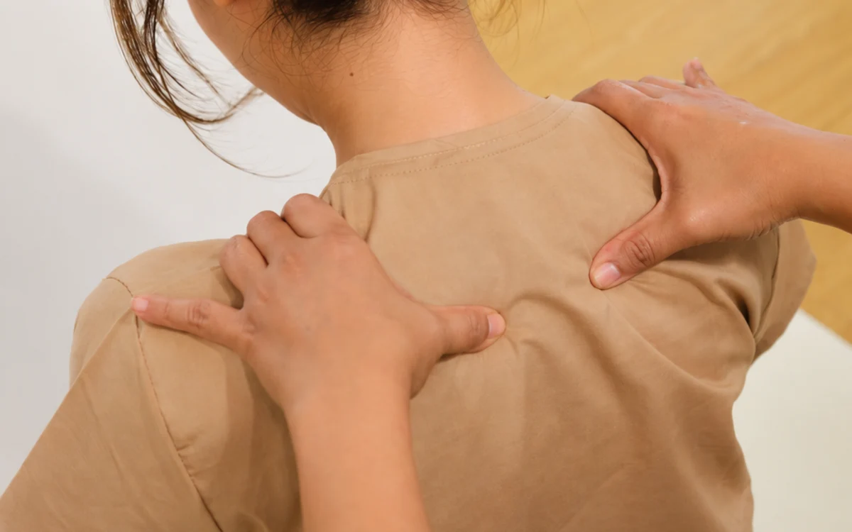 A therapist’s hands working around a guest’s neck and shoulders from behind