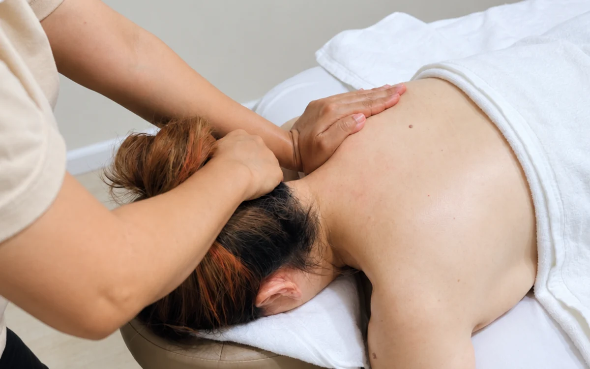 A therapist’s hands attending to the base of a guest’s neck and the back of the head